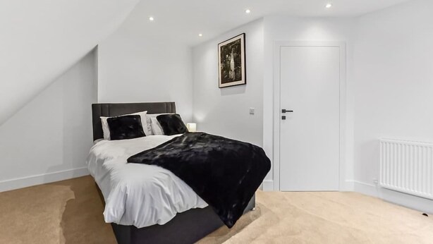 A bedroom with a bed, a door, and a radiator. - Stylish East Croydon Apartment w Balcony Fast Wifi (Croydon)