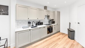 A modern kitchen with white cabinetry, a black sink, and a microwave. - Stylish East Croydon Apartment w Balcony Fast Wifi (Croydon)