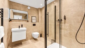 Une salle de bain moderne avec une douche à parois de verre, un lavabo blanc et des toilettes.