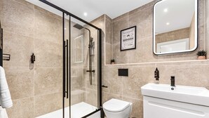 A modern bathroom with a glass-enclosed shower, a toilet, and a sink with a mirror above. - Modern 1 Bedroom Stay Balcony East Croydon (Croydon)