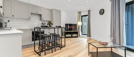 Una cocina moderna con comedor, televisor y un amplio ventanal con cortinas.
