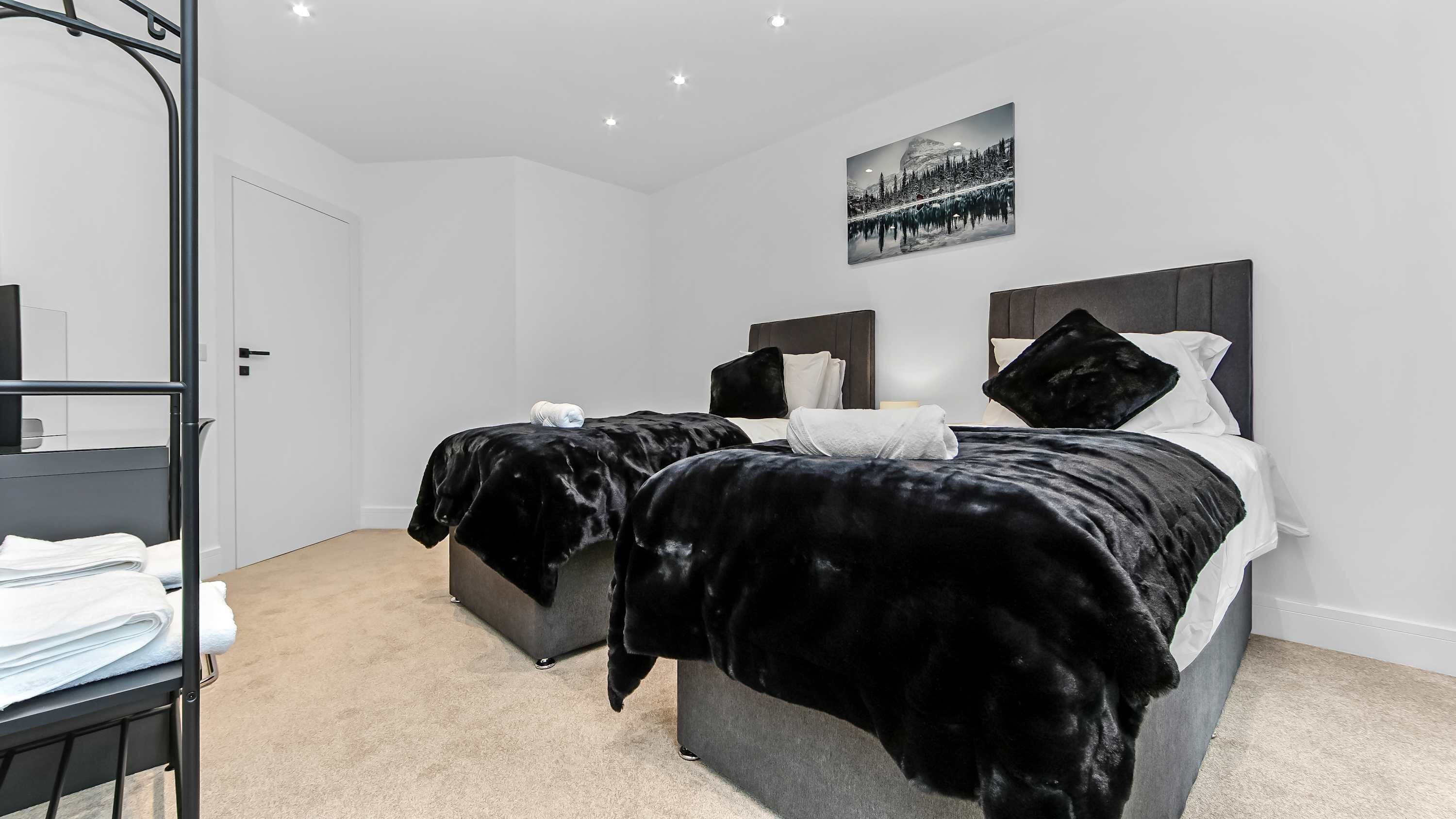 Een slaapkamer met twee bedden, een stapelbed, een schilderij en een spiegel.