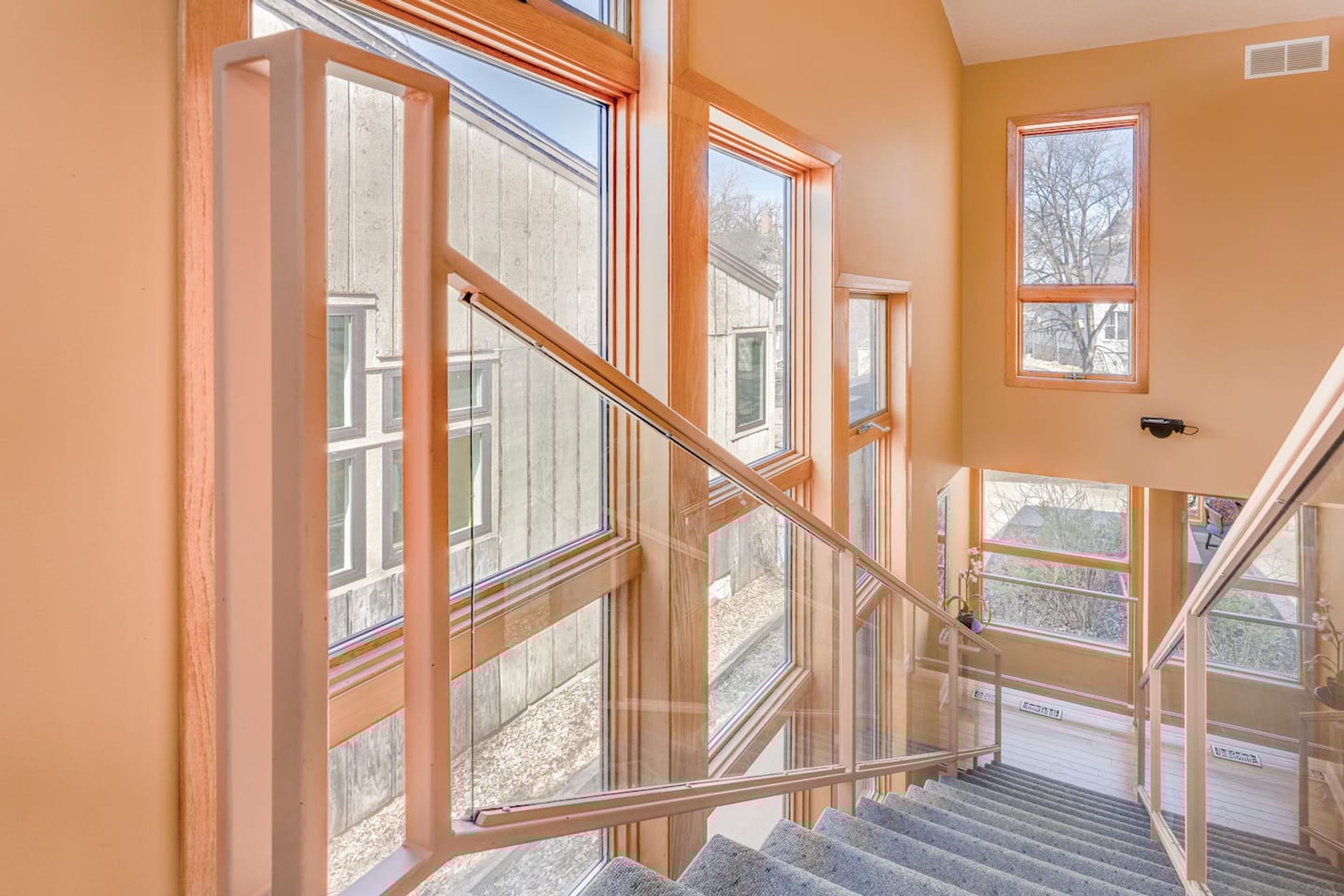 A staircase with glass railings and multiple windows, leading to an outdoor area.