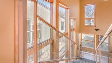 A staircase with glass railings and multiple windows, leading to an outdoor area.