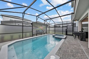 Ein überdachter Innenpool mit Glasdach, einem Whirlpool und einer Lounge mit Blick auf eine Rennstrecke.
