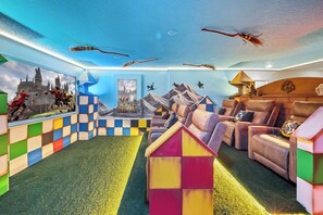 A room with a checkered floor, a colorful playhouse, a sofa set, and wall art depicting scenes from a wizarding world. - 7BR house at Windsor Cay Resort (Clermont)