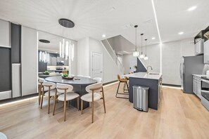 Une cuisine moderne dotée d’un îlot central, de tabourets de bar et d’un escalier menant à un niveau supérieur.