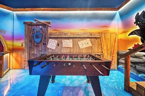 A foosball table in a room with a wooden wall and a mural of a sunset. - 7BR house at Windsor Cay Resort (Clermont)