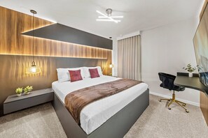 A modern hotel room with a large bed, bedside lamps, a desk, and a television. - 7BR house at Windsor Cay Resort (Clermont)