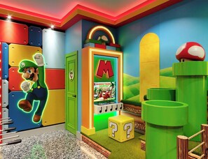 Um quarto colorido com um personagem do Mario, um aparelho de jogos e uma porta verde.