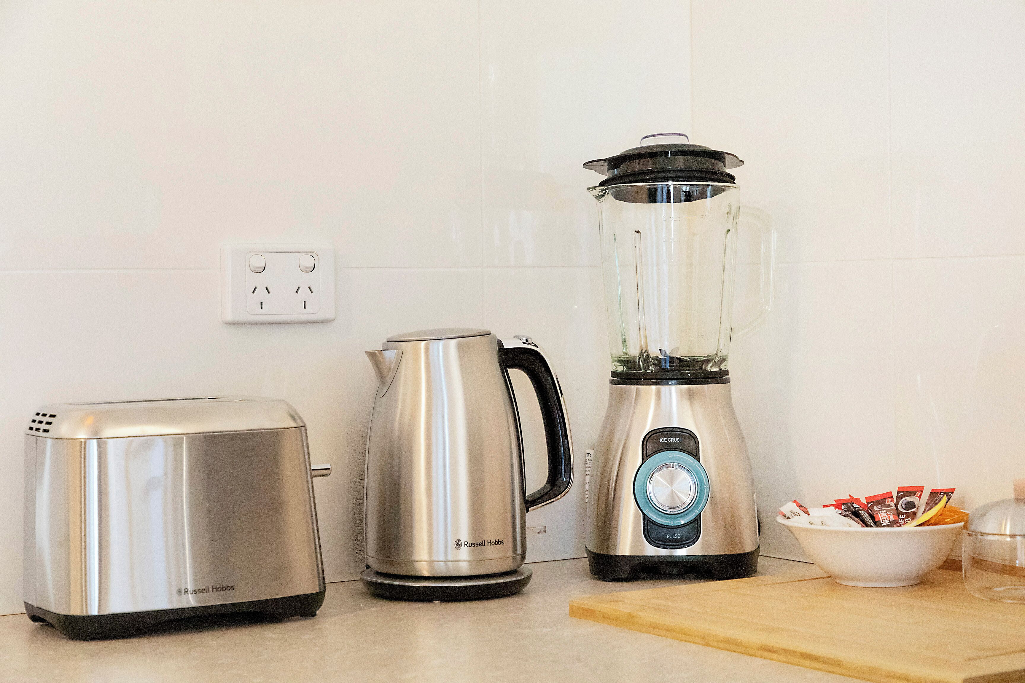 A kitchen with a toaster, a kettle, and a blender on the counter.