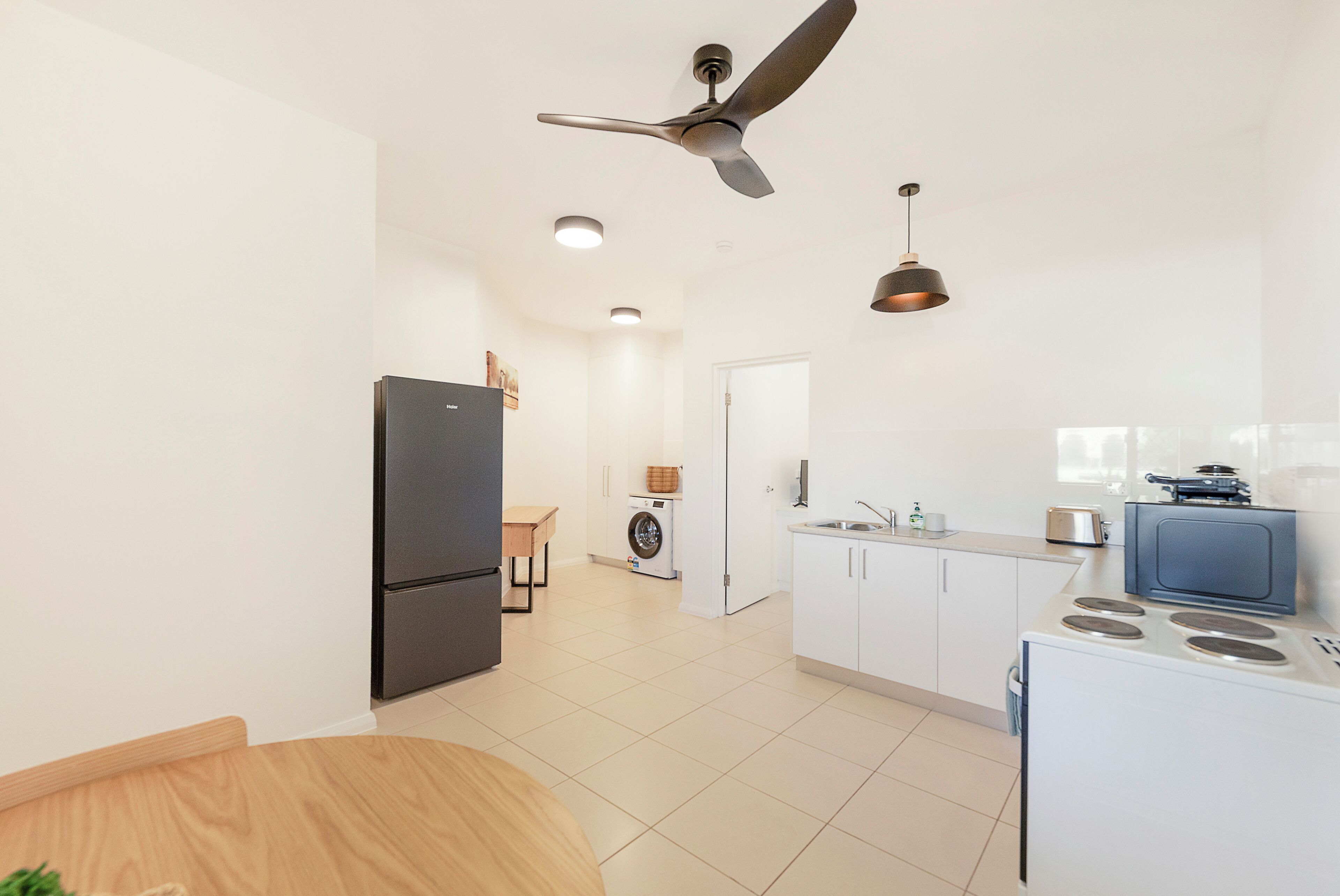 A modern kitchen with a refrigerator, stove, and ceiling fan.