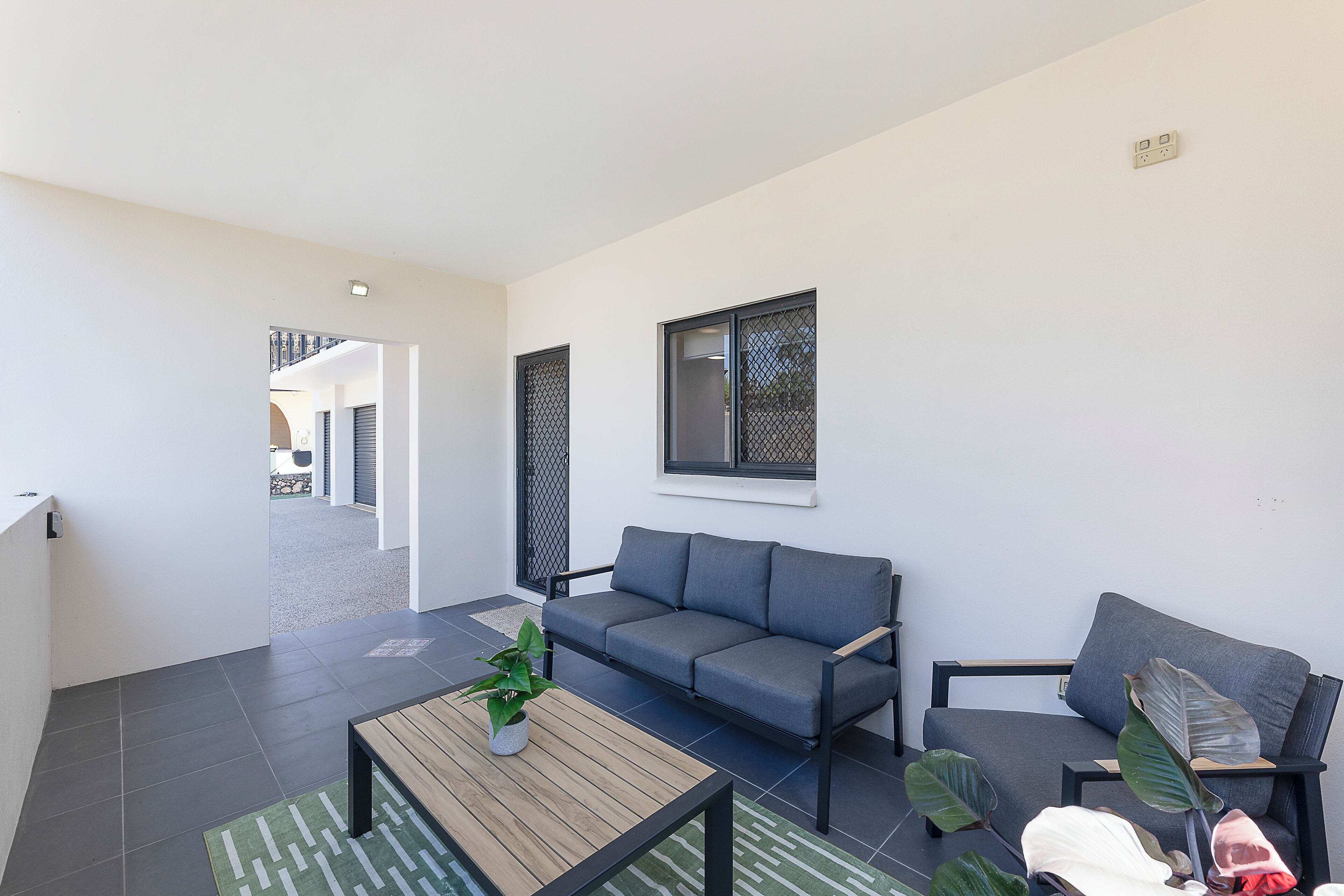 A modern living room with a grey sofa, a wooden coffee table, and a potted plant.