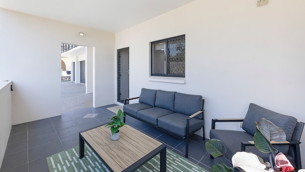 A modern living room with a grey sofa, a wooden coffee table, and a potted plant.