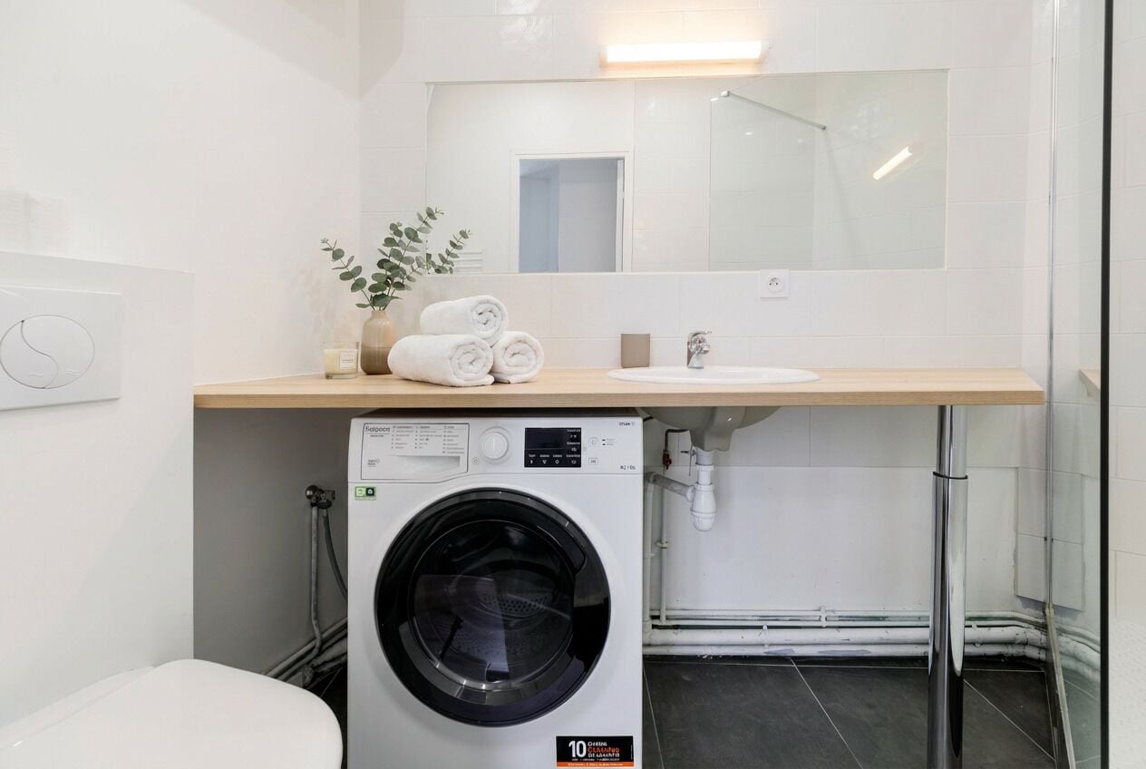 Un baño moderno con lavadora, lavamanos y espejo.