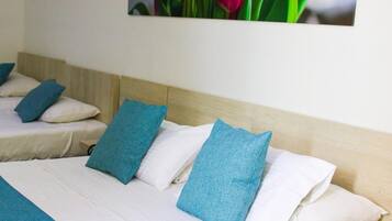 Habitación de hotel con cama, almohadas y un cuadro de flores colgado en la pared.