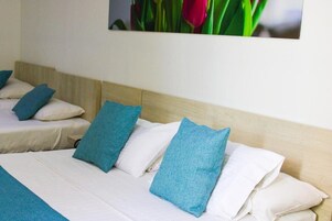 Habitación de hotel con cama, almohadas y un cuadro de flores colgado en la pared.