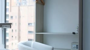 Habitación moderna con un armario blanco, una silla y vistas a edificios.