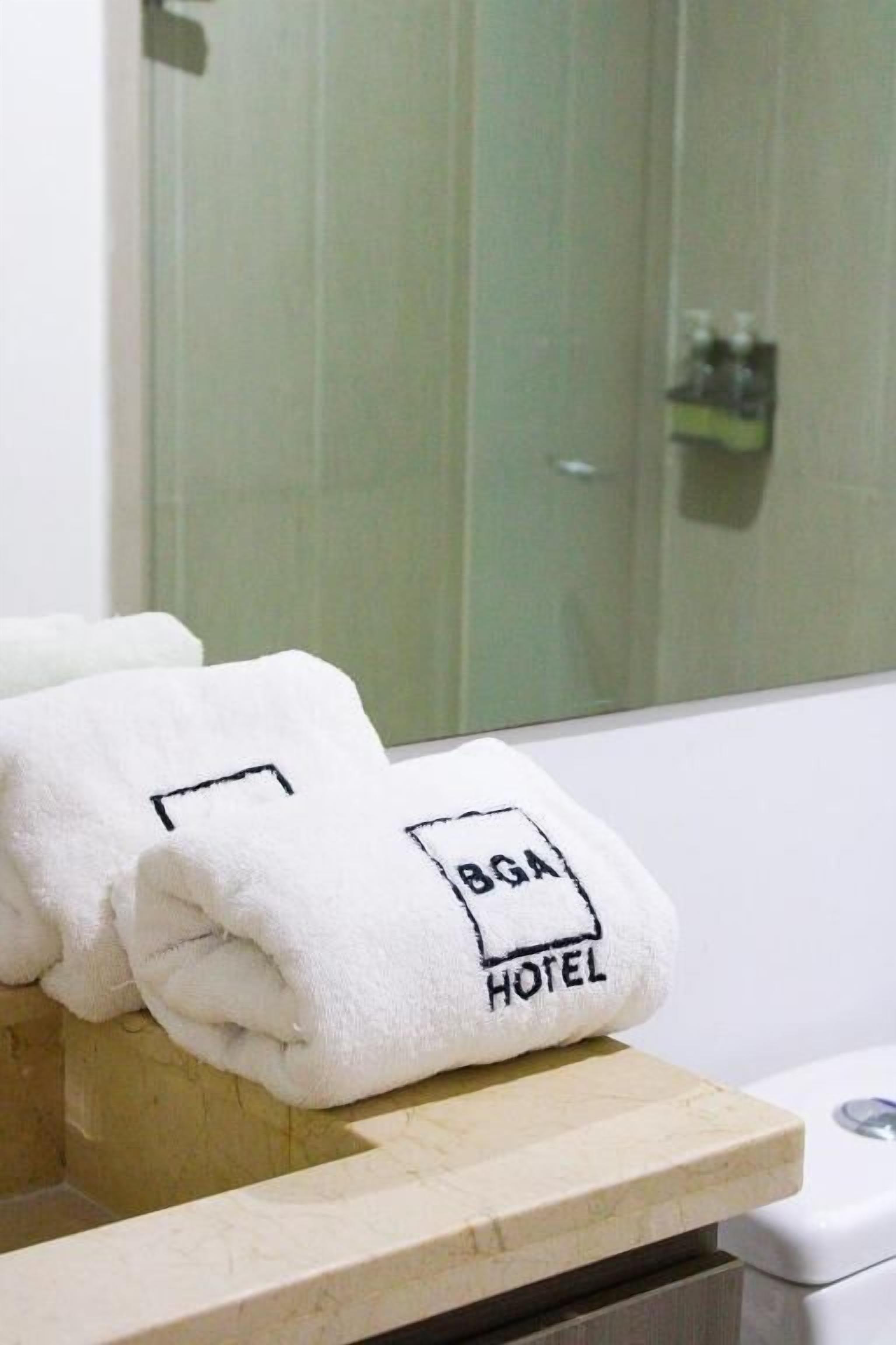 A bathroom with a white bathtub, a towel rack with folded towels, and a glass shower door.