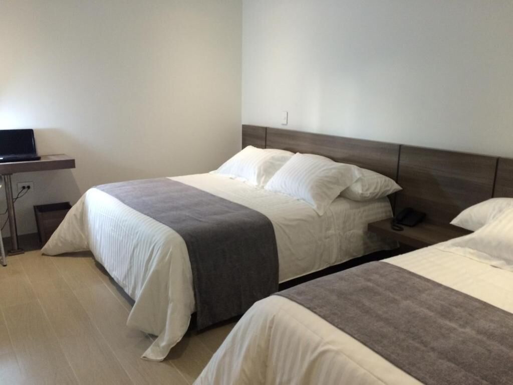 A hotel room with two beds, a bedside table, and a television.