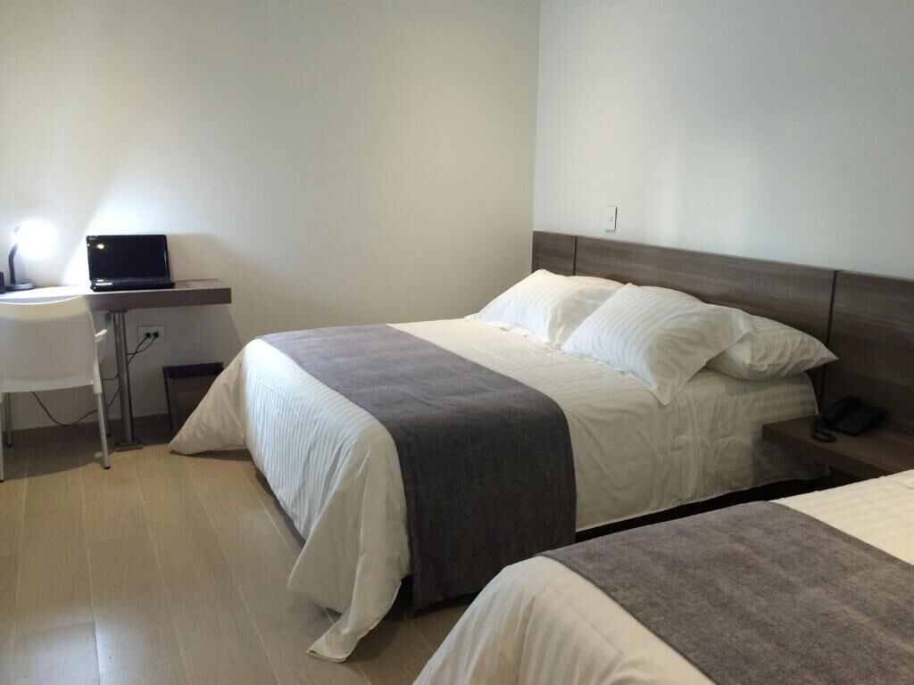 Une chambre d’hôtel avec deux lits, un bureau avec un ordinateur portable et une table de chevet avec un téléphone.