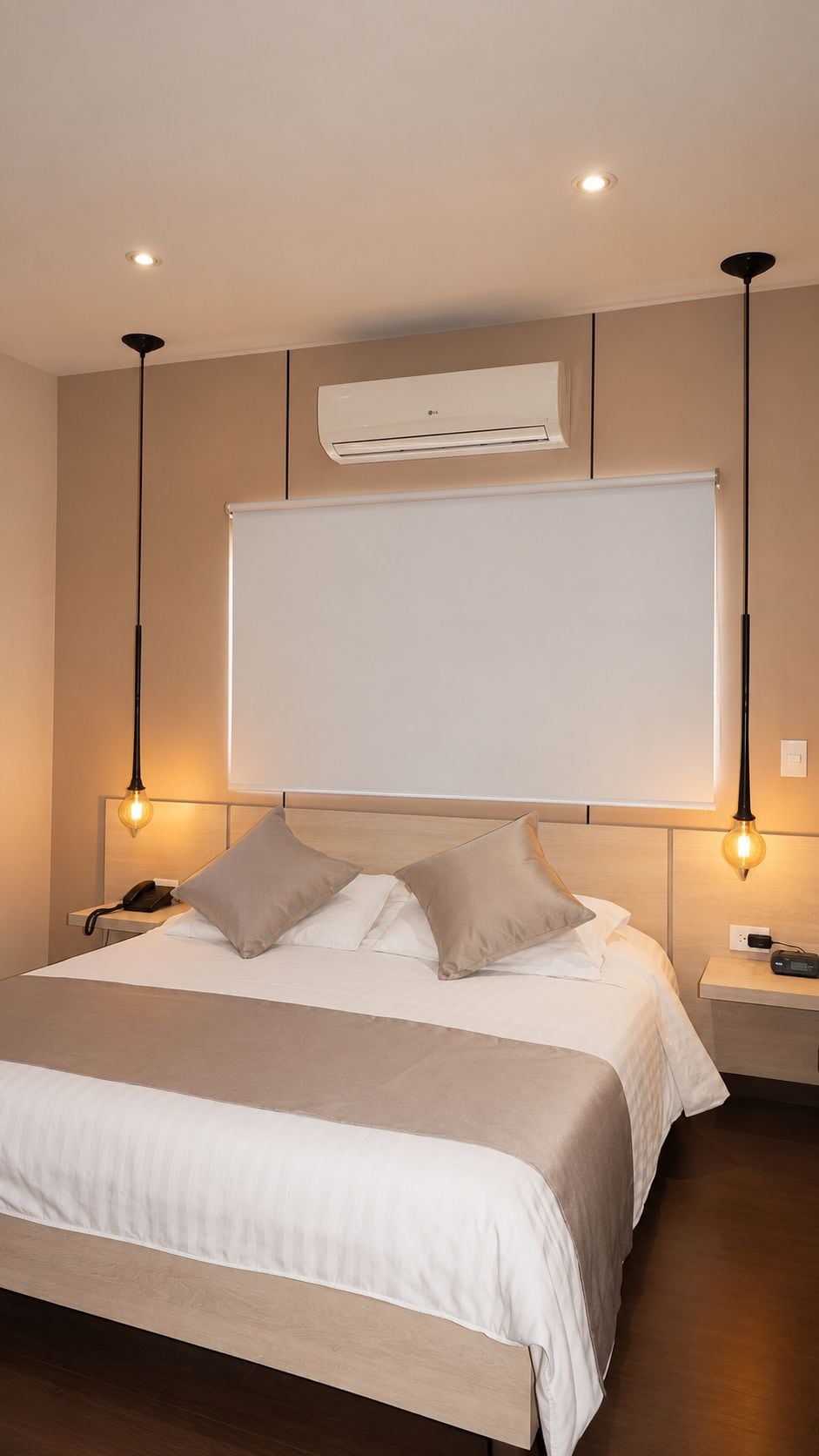 A hotel room with a bed, bedside tables, an air conditioning unit, and pendant lighting.