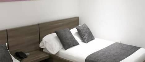 Quarto de hotel moderno com duas camas, uma mesa de cabeceira e um quadro pendurado na parede.