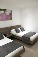 A modern hotel room with two beds, a nightstand, and a wall-mounted painting.