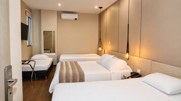 Habitación de hotel con dos camas, televisión, aire acondicionado y mesita de noche con teléfono.