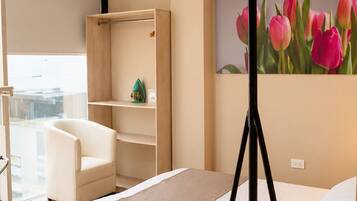 Una habitación de hotel con una cama, un escritorio, una silla, un cuadro de tulipanes y una lámpara colgante.