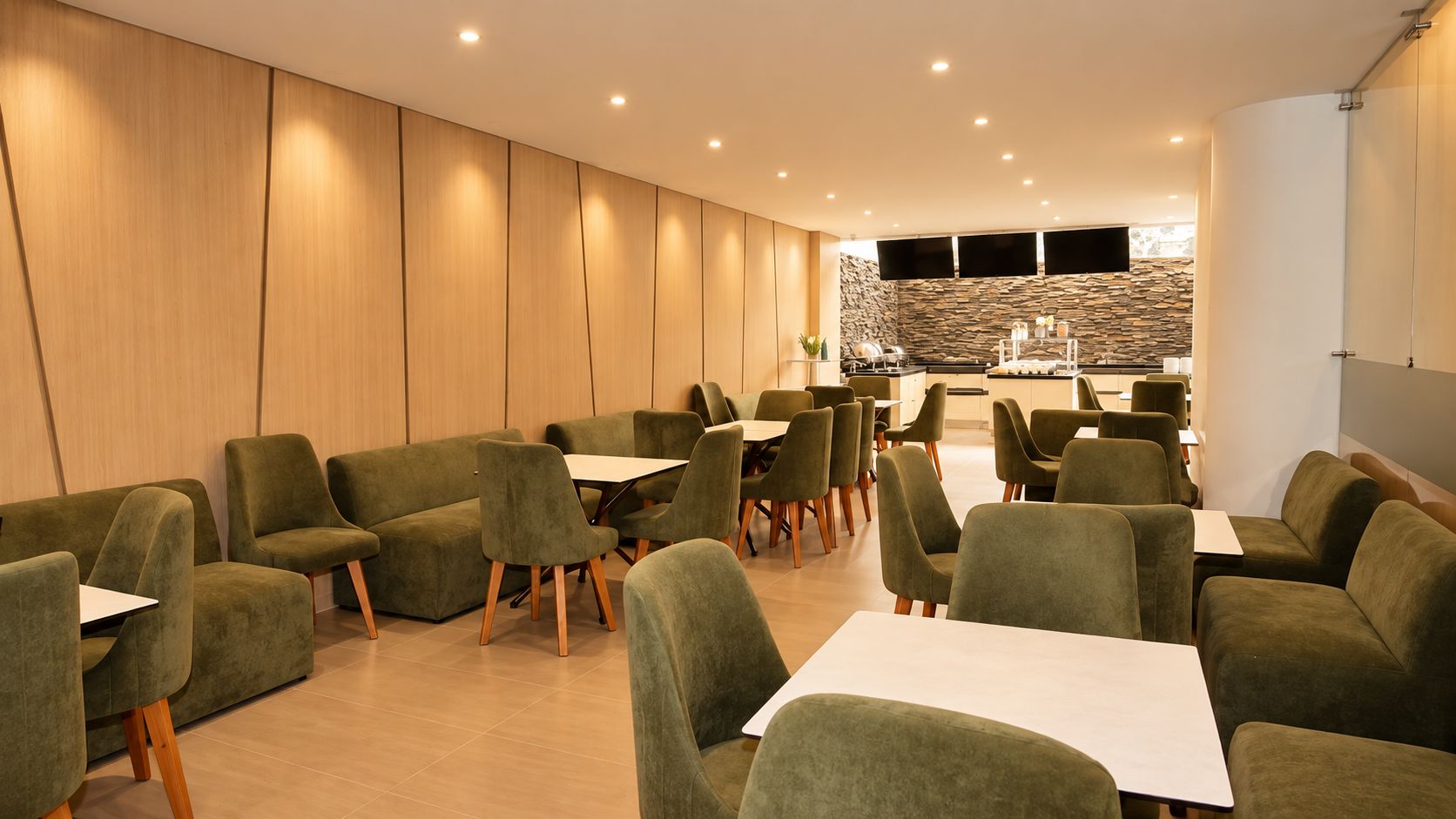 A modern dining area with green upholstered chairs and tables, a stone wall, and recessed lighting.