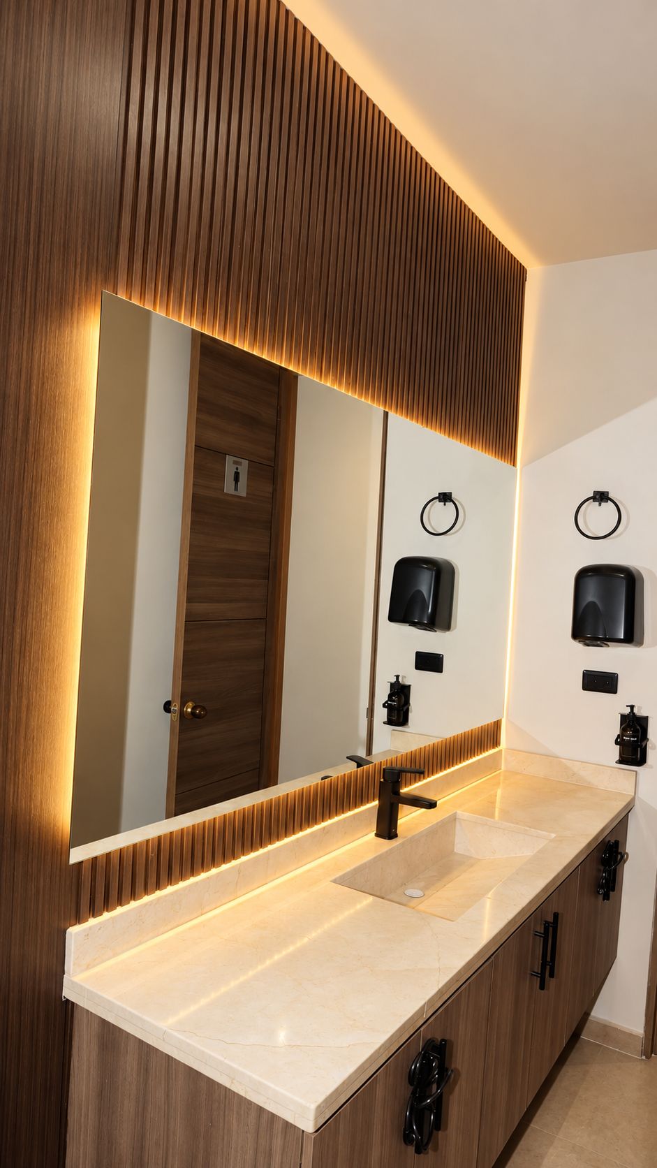 A modern bathroom with a large mirror, a sink, and two towel dispensers.