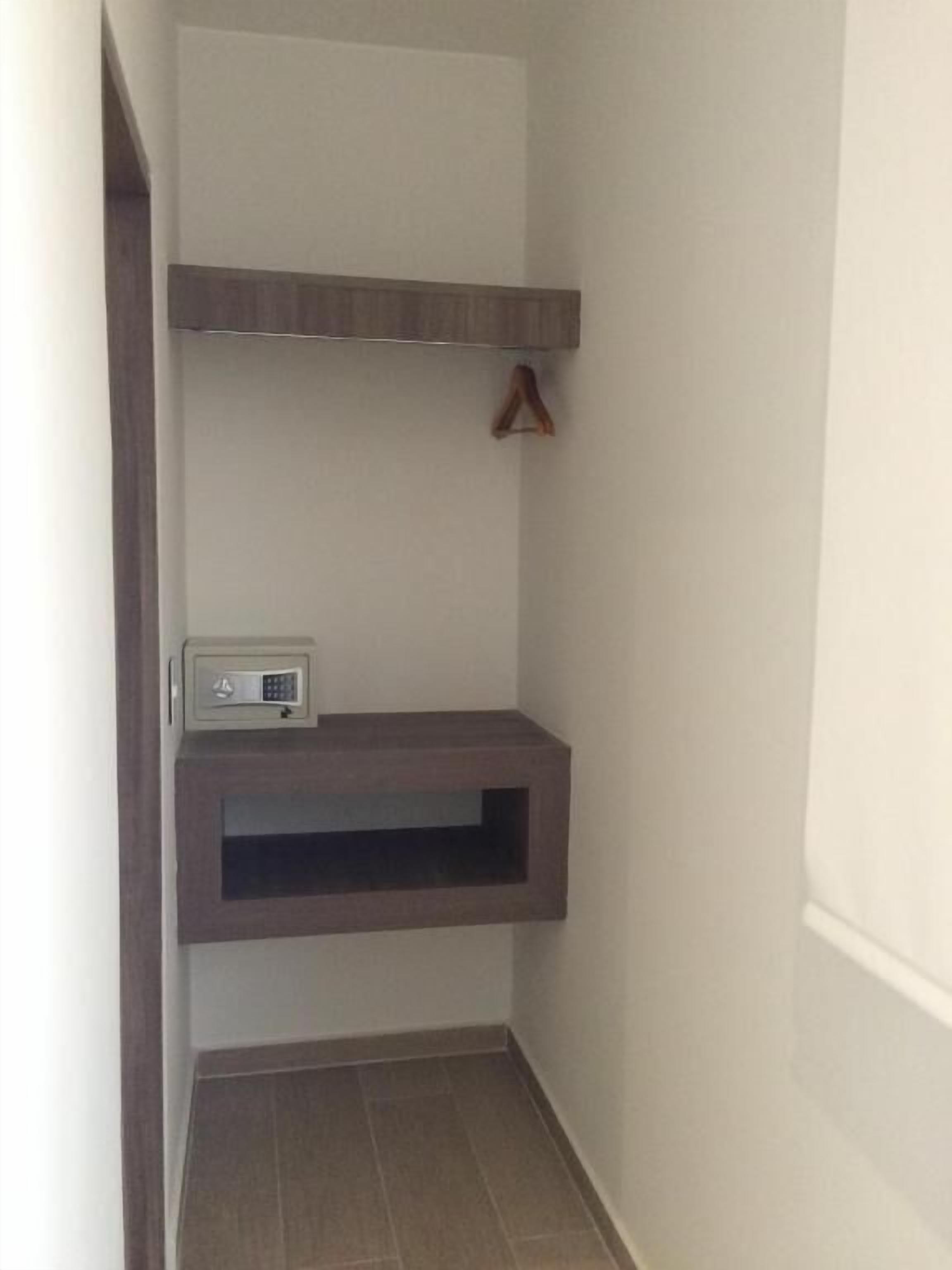 Un pasillo estrecho con un mueble empotrado y un pequeño dispositivo electrónico a la izquierda.