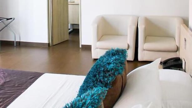 Habitación de hotel con cama, un cuadro de tulipanes en la pared y vista al pasillo.