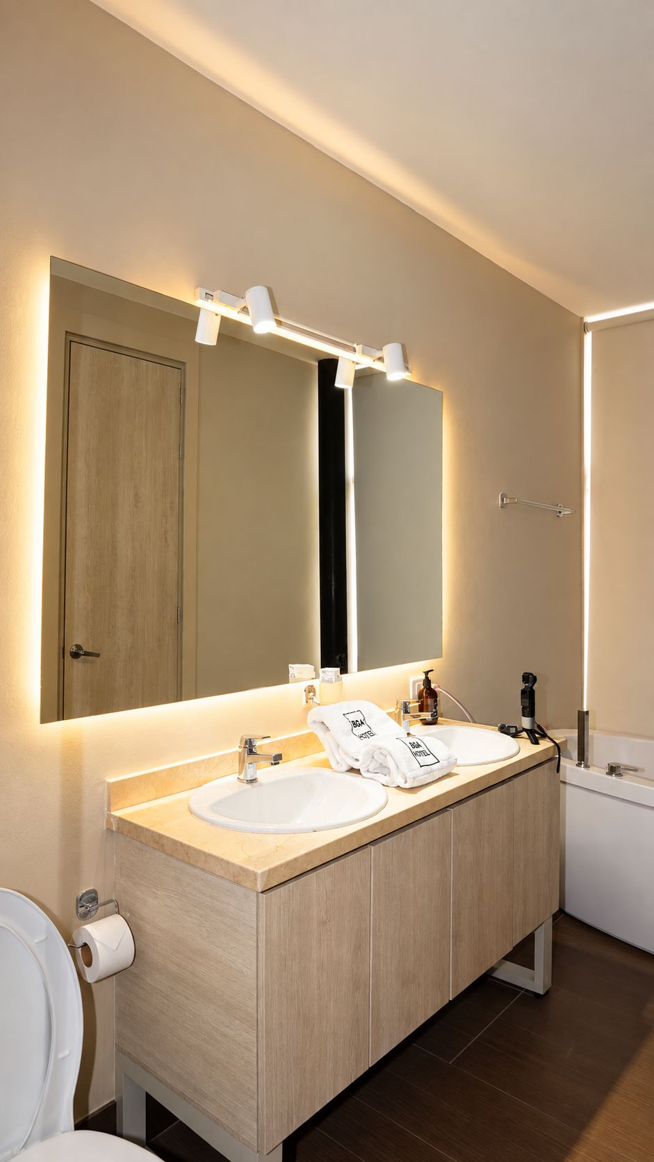 A modern bathroom with a double sink vanity, a large mirror, and a toilet.