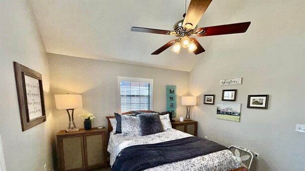 A bedroom with a bed, bedside lamps, a ceiling fan, and a window with blinds. - The Escape on Blade Bay (Hardin County)