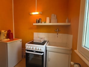 Eine kleine Küche mit Herd, Backofen und Kühlschrank.