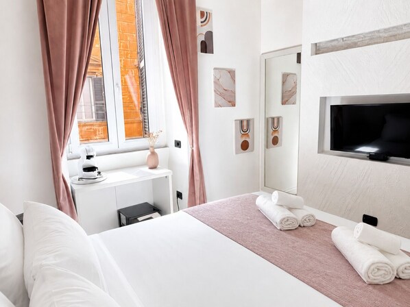 A hotel room with a bed, a desk, a TV, and a window with curtains.