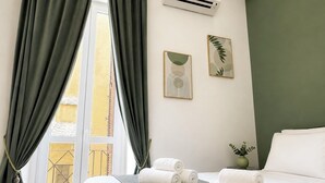 Ein Hotelzimmer mit einem Bett, gerollten Handtüchern, einem Fenster mit Vorhängen und Wandbildern.