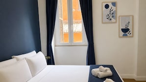 Ein Hotelzimmer mit einem Bett, einem Fenster mit Vorhängen und zwei Wandbildern.