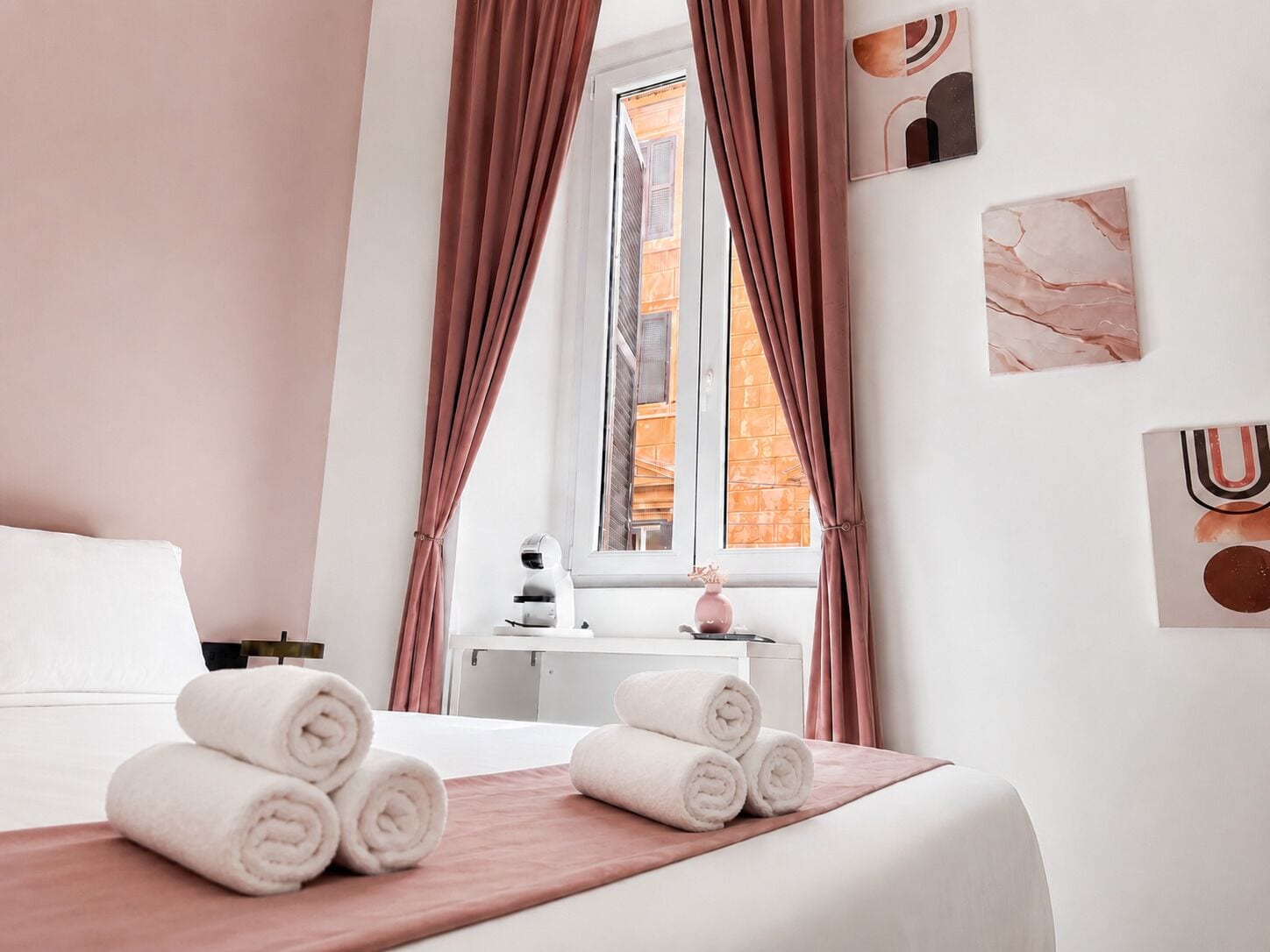 A hotel room with a bed, towels, a nightstand, a lamp, and a window with curtains.