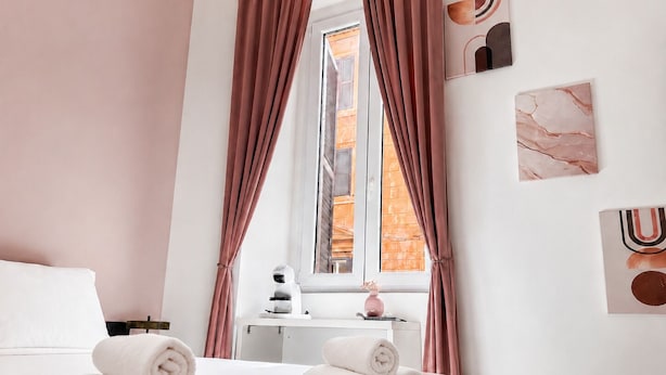 Ein Hotelzimmer mit Bett, Handtüchern, einem Nachttisch, einer Lampe und einem Fenster mit Vorhängen.