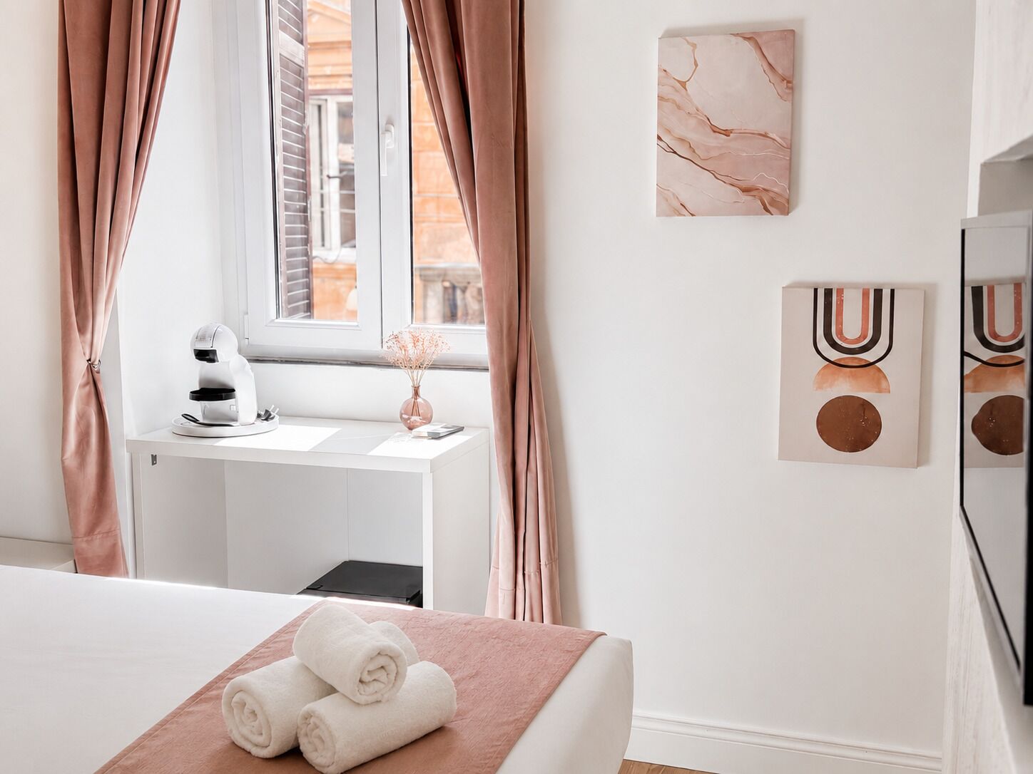 Una habitación de hotel con cama, escritorio con computadora, ventana con cortinas y decoración en la pared.