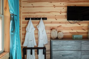 Eine Holzwand mit einem angebrachten Fernseher, einem Handtuchhalter und einem Schrank mit Schubladen.