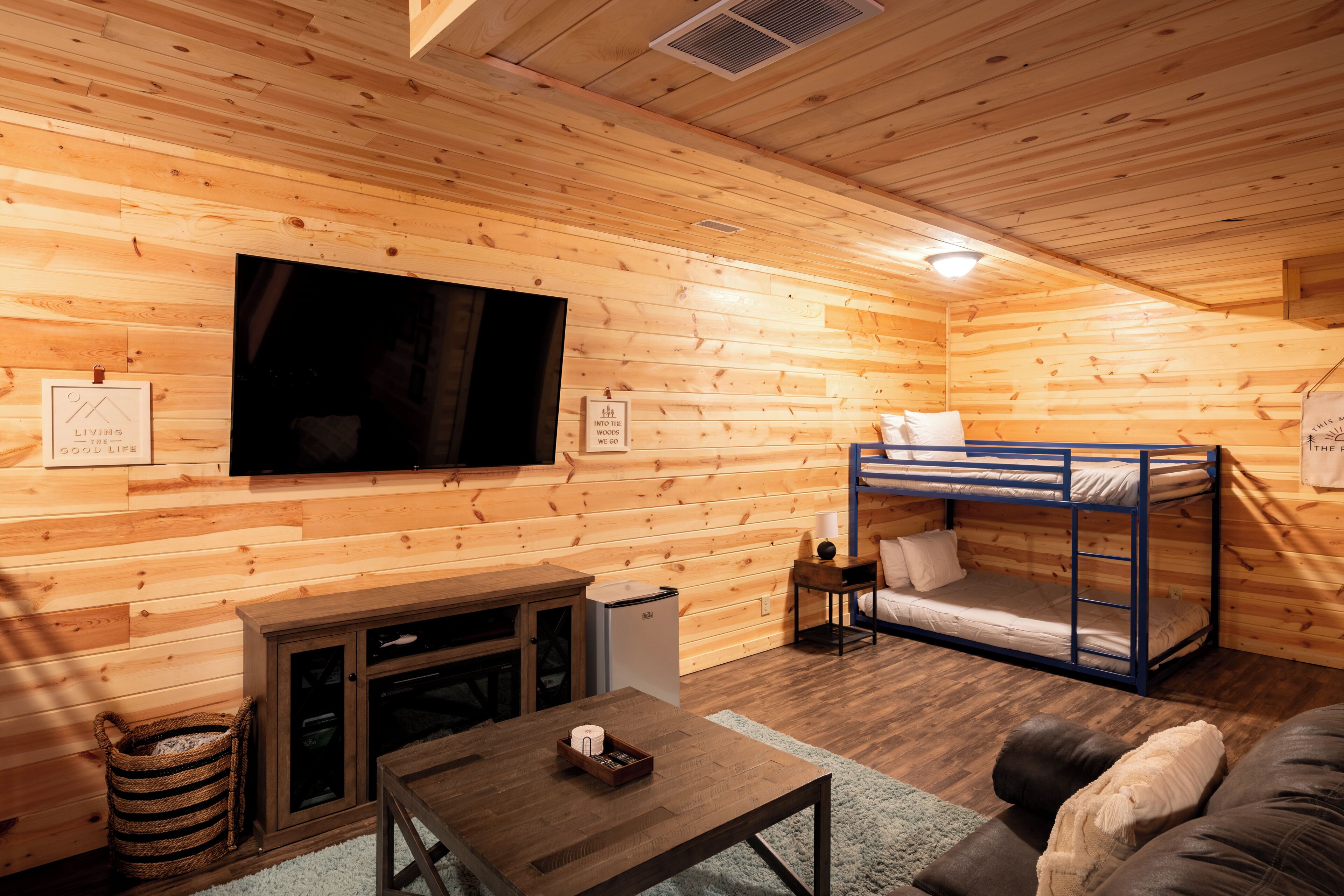 L’intérieur chaleureux d’un chalet avec une télévision, des lits superposés, une petite table et une cheminée.