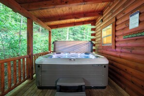 A hot tub in a wooden cabin with a wooden deck and a view of the forest. - 5 Minutes to Ash Cave! Sleeps 10 w/3 Private Bedrooms + Hot Tub + WiFi + Games (South Bloomingville)