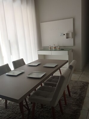 A modern dining area with a long table, chairs, and a kitchen area in the background. - Fully furnished house, everything included. (Betim)
