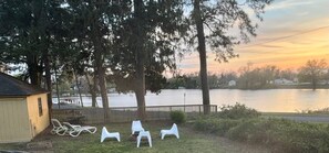 A lakeside property with a small shed, a wooden fence, and several white plastic chairs. - On Johnson Pond _ Near Downtown and SU (Salisbury)