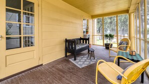 A covered porch with a wooden bench, a small stool, and a yellow chair. - On Johnson Pond _ Near Downtown and SU (Salisbury)