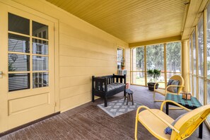 A covered porch with a wooden bench, a small stool, and a yellow chair. - On Johnson Pond _ Near Downtown and SU (Salisbury)